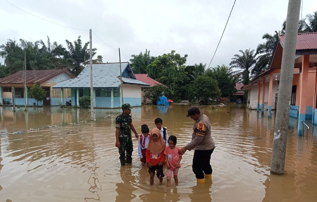 Banjir di Kabupaten Rokan Hulu, Babinsa bersama Bhabinkamtibmas Antar Jemput Anak Sekolah 